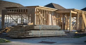 Building Material Prices rising, house being built with lumber stacked in front