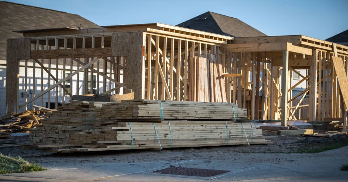 Building Material Prices rising, house being built with lumber stacked in front